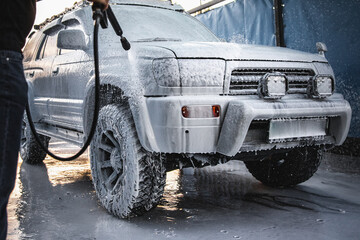 Man treating his car with white foam at a self-service car wash.