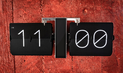 Flip black clock with eleven o'clock time on panel closeup. Clock with hours and minutes numbers