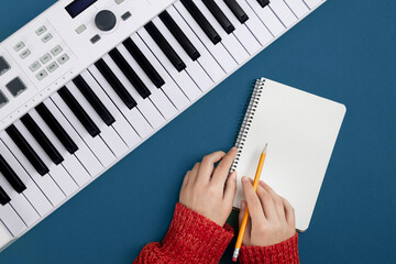 Female hands, empty notepad and music keys on blue background, flat lay, musical creativity concept.