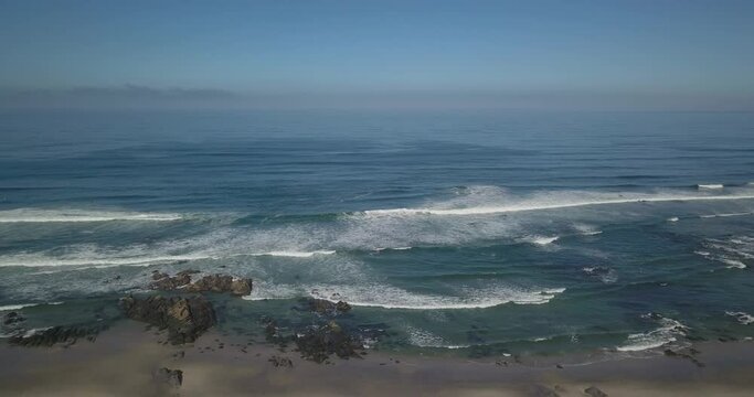 Clean white sand beach with rocks and cliffs and turquoise water.