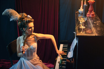 Emotions. Portrait of young beautiful woman in image of medieval person sitting at the piano in elegant white dress and playing. Comparison of eras, beauty, history, art