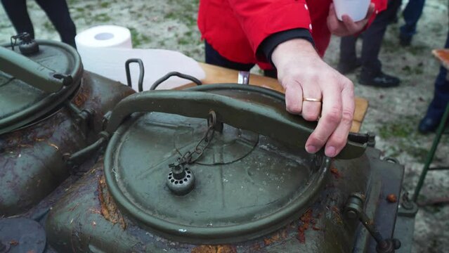 Cooking hunter's stew in a field kitchen during the winter and pouring it into a cup