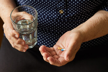 Retired woman with a glass of water is going to take pills