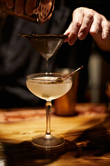 Barman making a martini cocktail at a bar