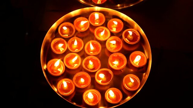 A female hand holding oil lamps plate in hand during deepavali festival. Diya or traditional clay lamps on Diwali festival. Indian Hindu religious ritual tradition at Diwali. 4K Slow Motion.
