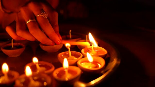 A female hand holding oil lamps plate in hand during deepavali festival. Diya or traditional clay lamps on Diwali festival. Indian Hindu religious ritual tradition at Diwali. 4K Slow Motion.