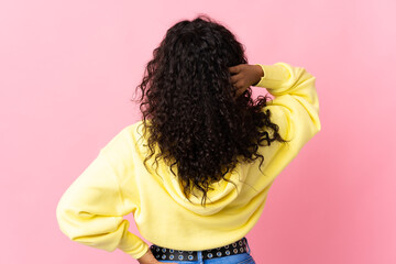 Teenager cuban girl isolated on pink background in back position and thinking