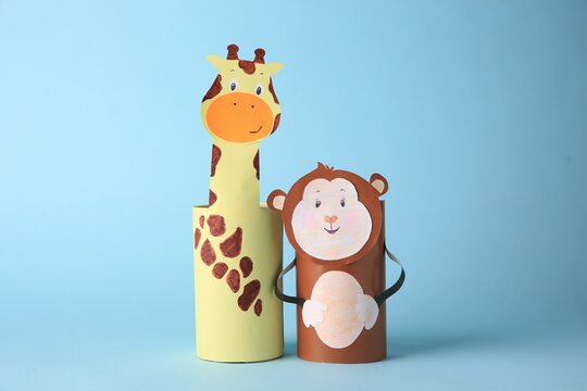 Toy monkey and giraffe made from toilet paper hubs on light blue background. Children's handmade ideas