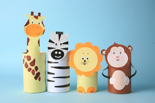 Toy monkey, giraffe, lion and zebra made from toilet paper hubs on light blue background. Children's handmade ideas