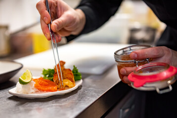 chef cooking slice salmon fish and shrimp with salad on kitchen
