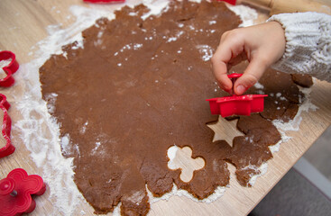 Child making Christmas cookies from Gingerbread dough and cookie cutters