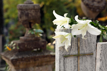 White lilies on granite tombstone outdoors, space for text. Funeral ceremony