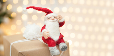Felted Santa toy sitting on a Christmas gift box