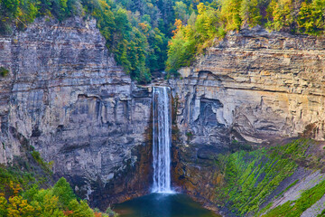 Fototapeta premium Huge waterfall flowing into large canyon with rocky cliffs