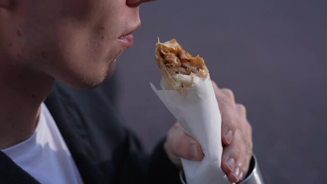 A young man eats shawarma