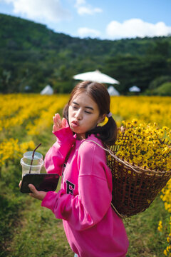 A woman wearing a pink dress is taking a walk in a yellow flower garden called Chrysanthemum during the day. At Pak Thong Chai District, Thailand 4-12-2022