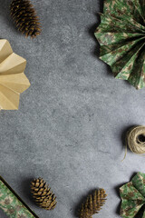 Frame with scandinavian paper christmas stars, pine cones, wrapping paper and skein of twine. Grey background. Festive handmade decorations. Copy space. Winter concept