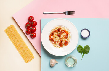 top view of pasta with meat near tomato, garlic, basil leaves and fork on beige pink blue background
