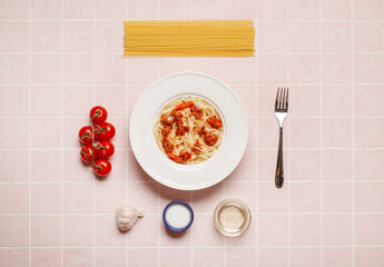 top view of pasta with meat near tomato, garlic, basil leaves and fork on pink background