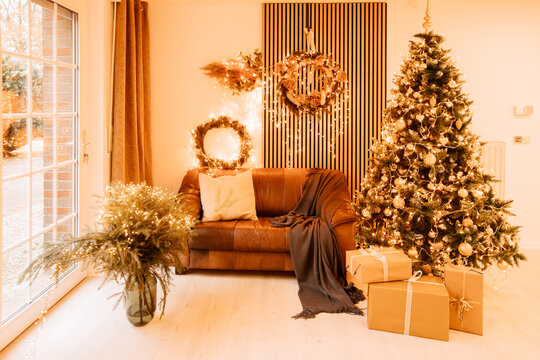 Beautiful artificial Christmas tree indoors next to a leather sofa. Beautifully decorated photo studio in Germany with wall panels. Christmas atmosphere in the new house. Acoustic panels in the house	