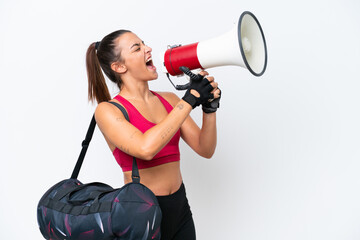 Young sport woman with sport bag isolated on white background shouting through a megaphone