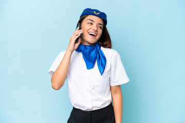 Airplane stewardess caucasian woman isolated on blue background keeping a conversation with the mobile phone