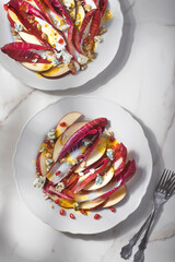 Sweet and salty salad with  Radicchio red chicory, pomegranate, red apples, nuts and blue cheese with date sauce. Recipes for winter salads from winter and late autumn ingredients.Gluten free diet