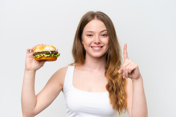 Young pretty woman holding a burger isolated on white background pointing up a great idea