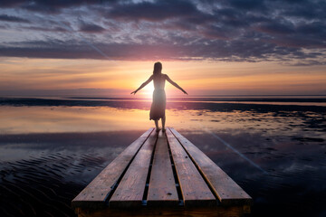 Eine Frau während einem Sonnenuntergang über dem Wattenmeer - 553481661