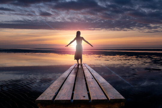 Eine Frau w&auml;hrend einem Sonnenuntergang &uuml;ber dem Wattenmeer