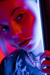 close up portrait of young and pretty woman with makeup near luminous neon lamp.
