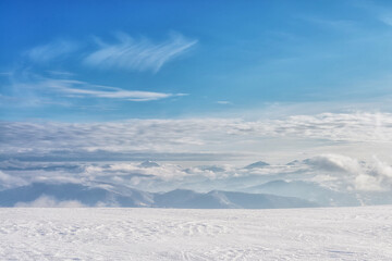 Clouds over a snow-covered mountain range. Winter mountain landscape.