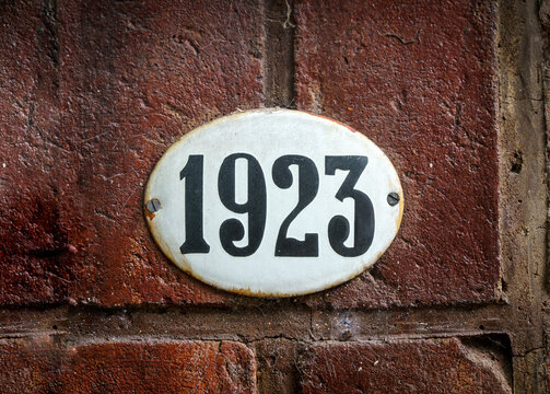Sign with the house number 1923 on the background of the wall.