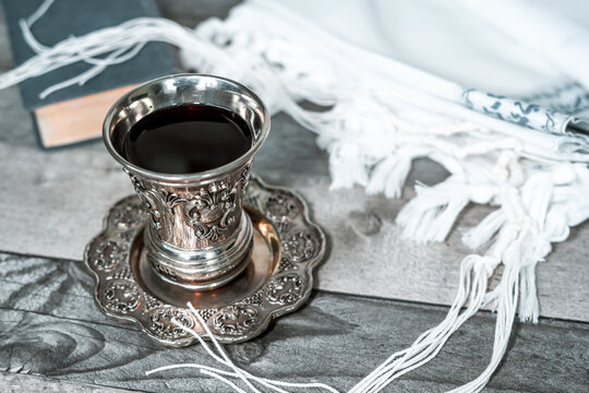 On the table is a silver glass for kiddush with shabbat wine, next to it lies a folded tallit and siddur (jewish prayer book) (132)