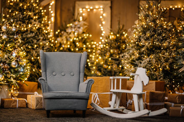 Christmas tree decorated in interior with armchair, nutcracker, presents and wooden horse 