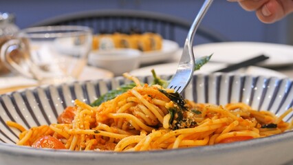 Close-up of spaghetti bolognese wound on a fork. Appetizing Italian pasta with tomatoes and basil. Delicious Italian dish in a plate wrap pasta on a fork for food. Eating at an Italian restaurant.