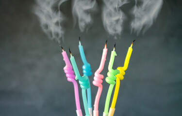Birthday candles with flame blown out smoke on dark background