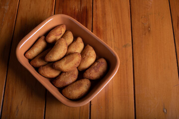 Por&ccedil;&atilde;o de risoles sobre mesa de madeira