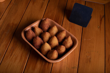 Por&ccedil;&atilde;o de coxinha sobre mesa de madeira com placa preta para informa&ccedil;&ocirc;es e valor