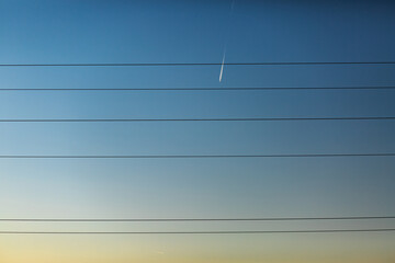Blue sky, lots of wires and a flying plane