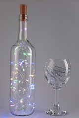christmas garland in a bottle with a glass on a gray background