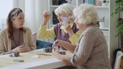 Joyful senior woman having fun while playing card game at home, game night - Powered by Adobe
