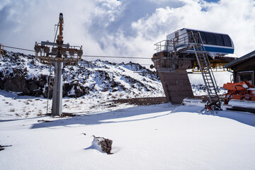 Cableway among snowy mountains under cloudy sky