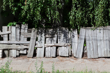 Old crooked wooden fence. Funny crooked fence in the shade of birch trees looks like a haunted...