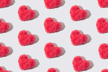 Pink fluffy plush hearts pattern on white background.