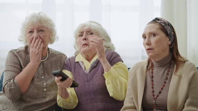 Shocked grandmas watching TV together, disturbed with negative media content