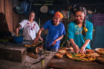 Mujeres Latinas preparando alimentos de maìs en una cocina antigua y con estufa de leña. 