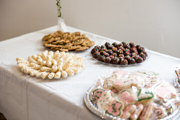 Dessert table with variety of plated cookies, lady lock cookies, cream horn cookies, chocolate chip cookies, chocolate truffle cookies