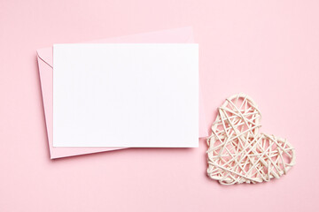 Card mockup, empty Valentines Day love letter with white heart on light pink background, top view, flat lay. Blank wedding invitation, white holiday greeting card
