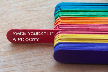 Make yourself a priority text on red wooden stick sticking out - Inspirational and motivational concept